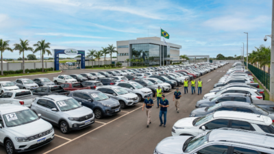 Pátio profissional de leilão de veículos no Brasil com carros organizados em fileiras e equipe de funcionários uniformizados